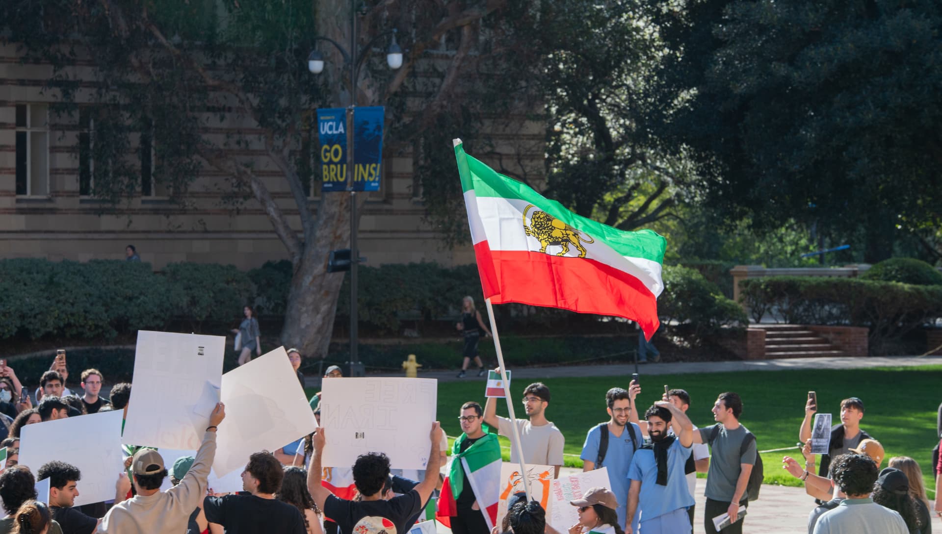 Iranian flag waving above a crowd gathered on campus