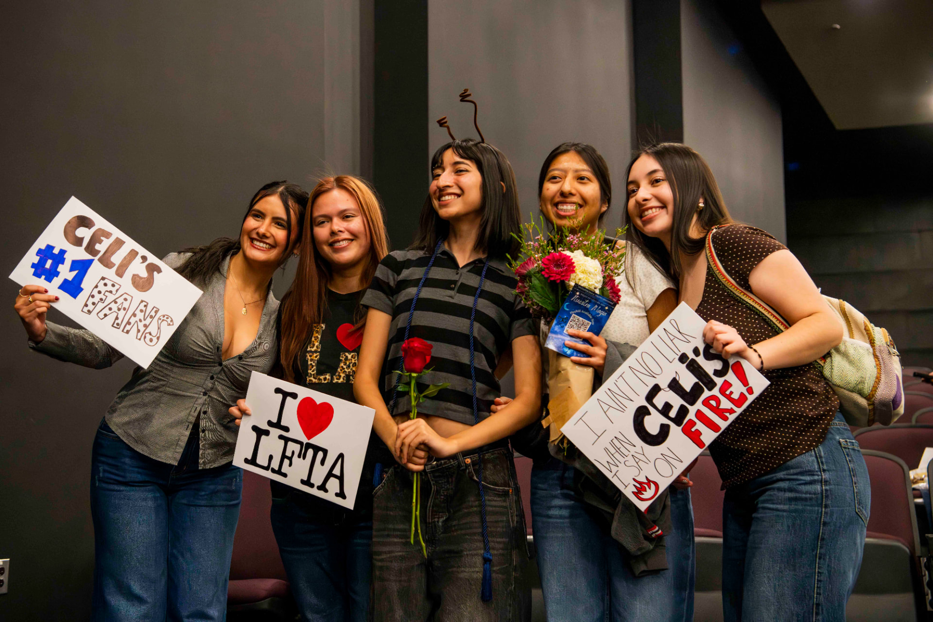 Friends holding handmade signs for a performer