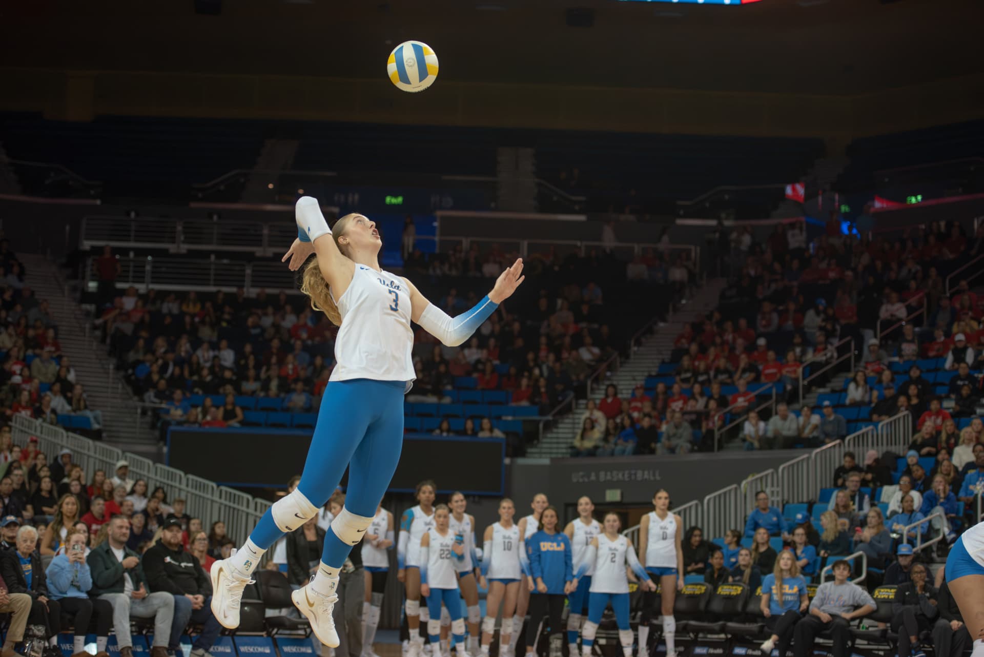 UCLA volleyball player serving mid-air