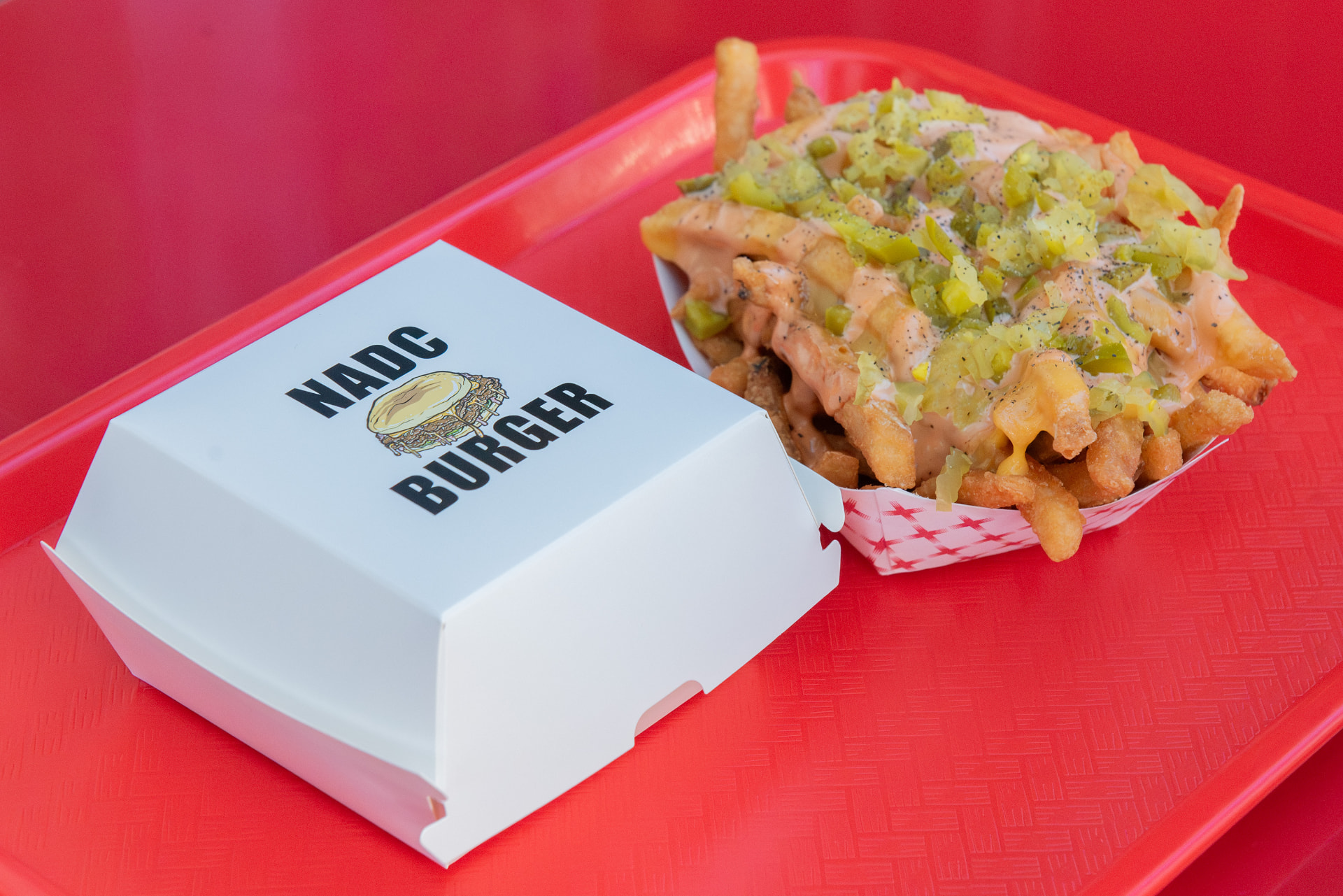 NADC Burger box beside animal-style fries on a red tray