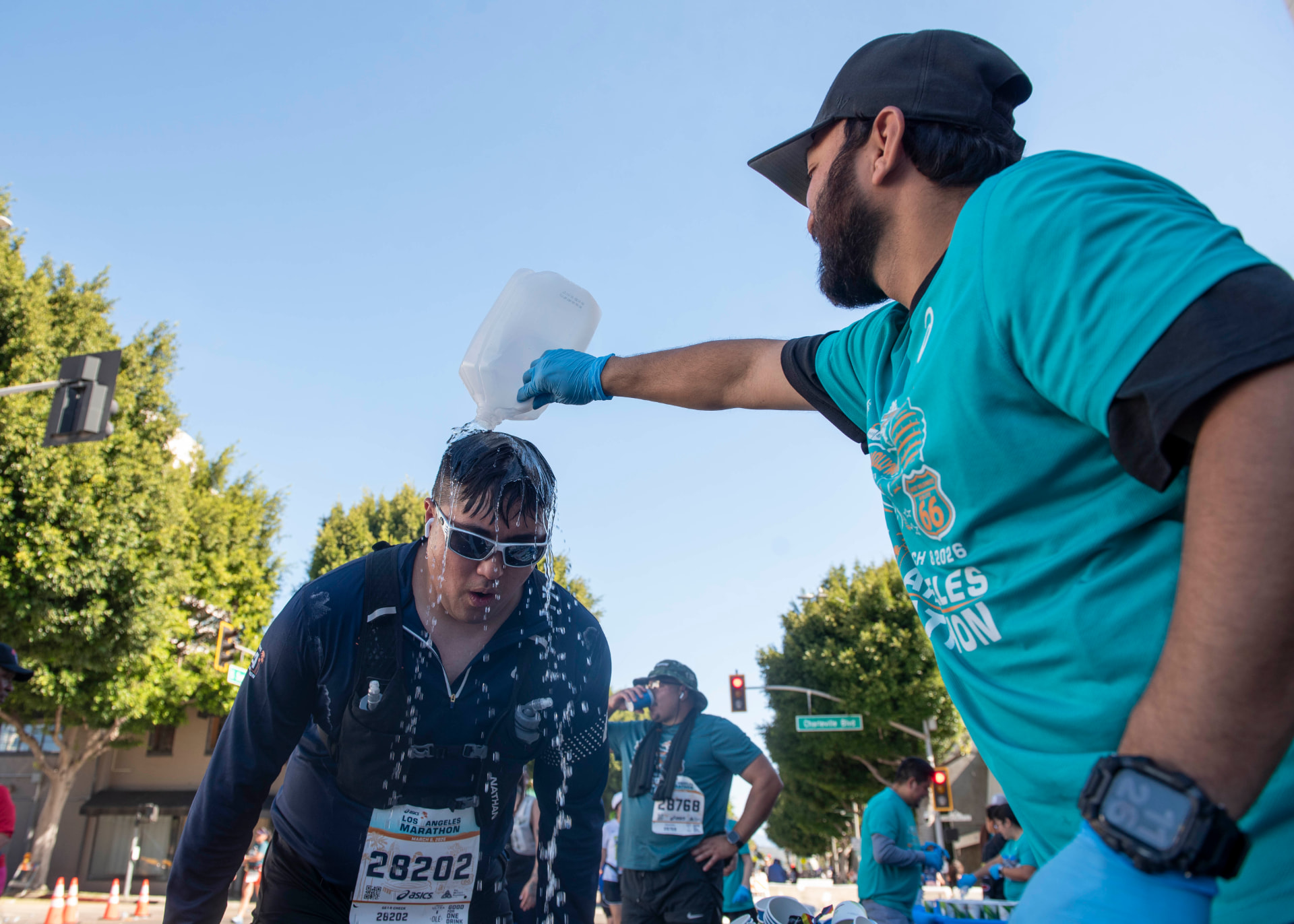 Volunteer pouring water over a marathon runner