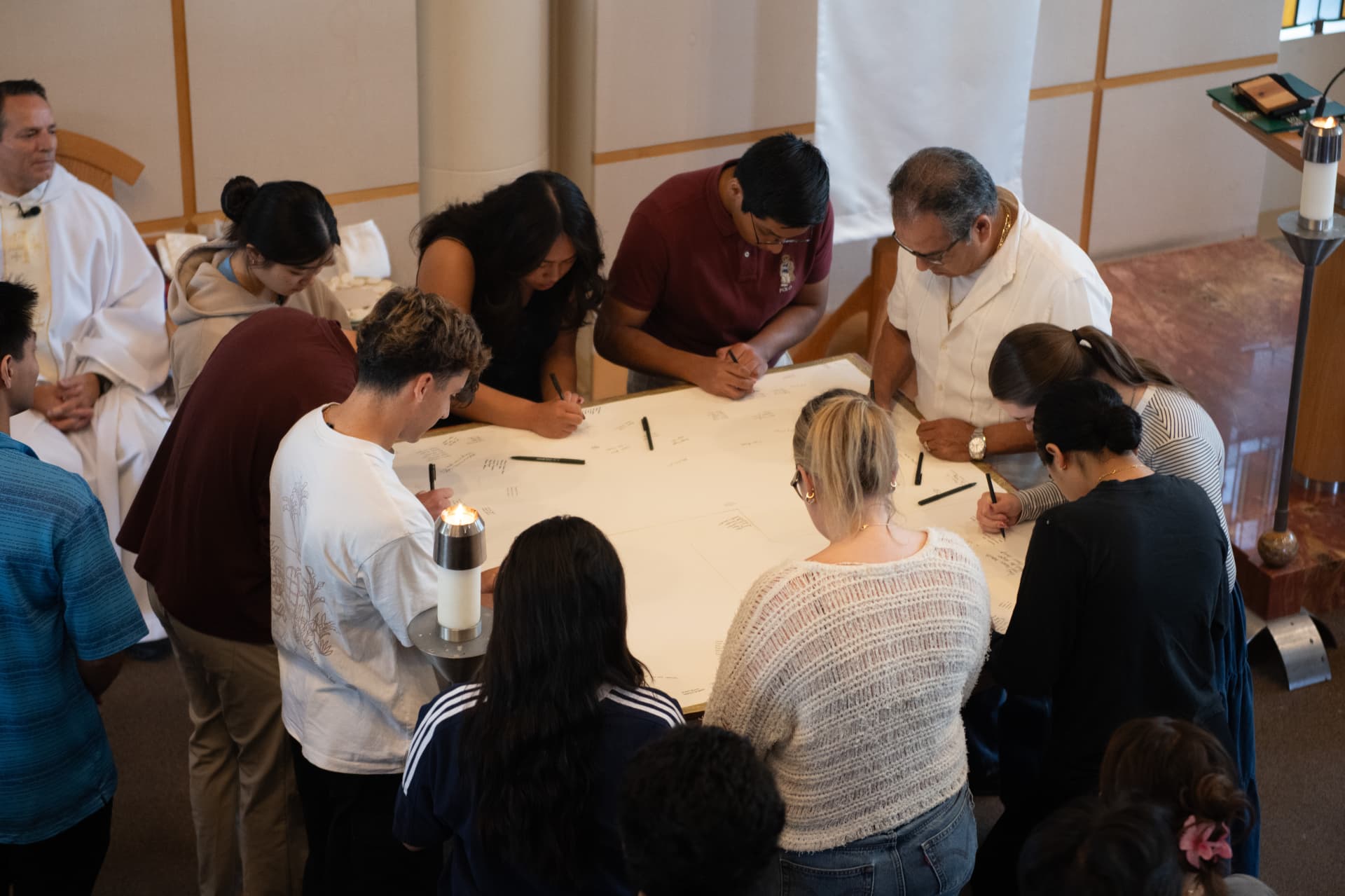 Community members signing a commemorative banner at an altar