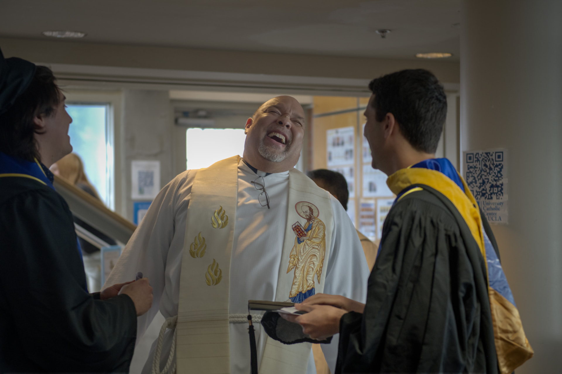 Chaplain laughing with graduates before a baccalaureate mass