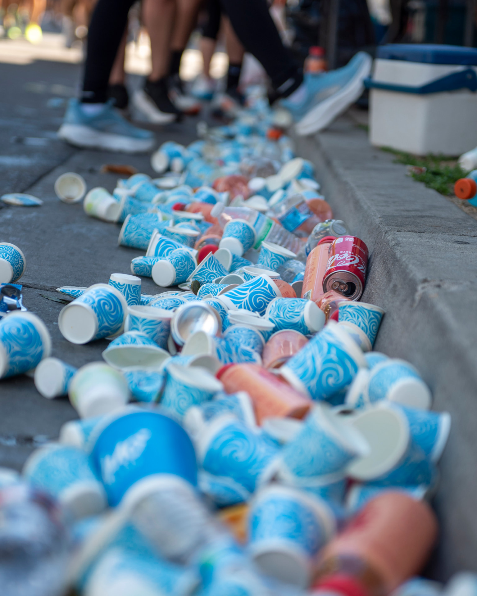 Discarded cups lining the curb at a marathon aid station