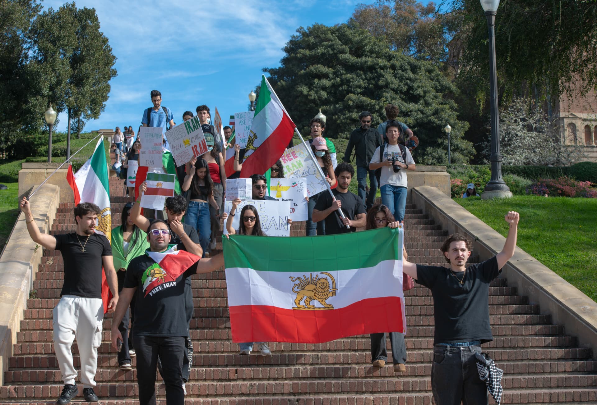 Demonstrators marching down campus steps with Iranian flags