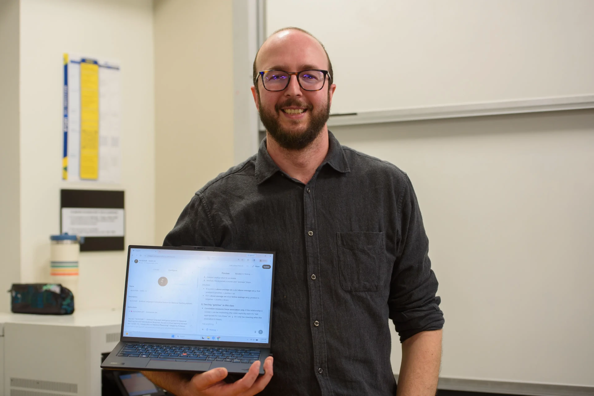 Instructor holding a laptop in a classroom